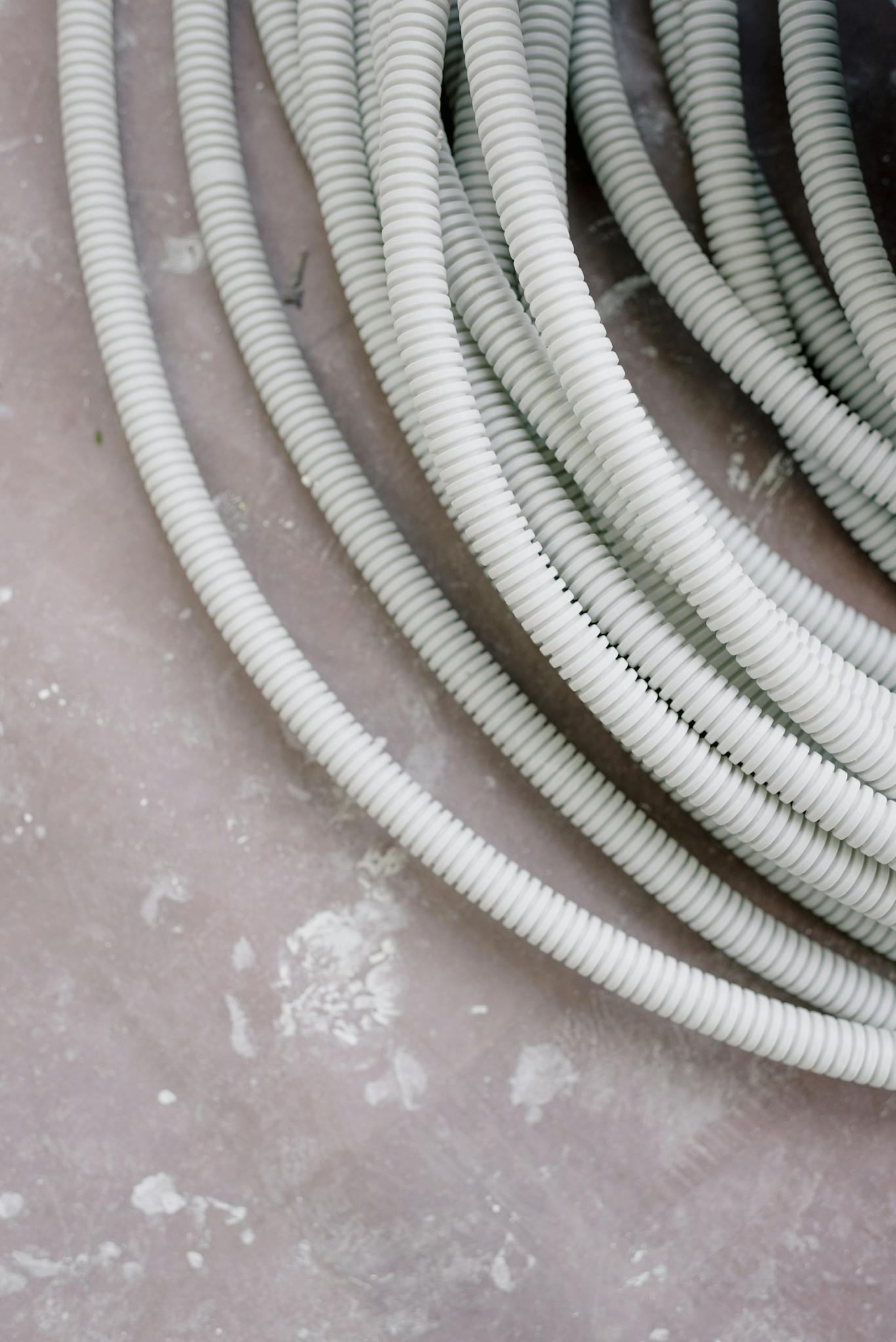Close-up of coiled white electrical wire on a rough, textured concrete surface.